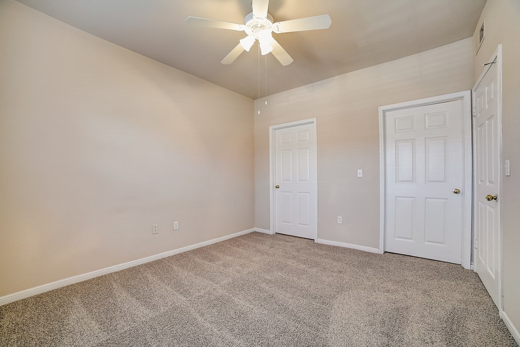 an empty living room with carpet and a ceiling fan