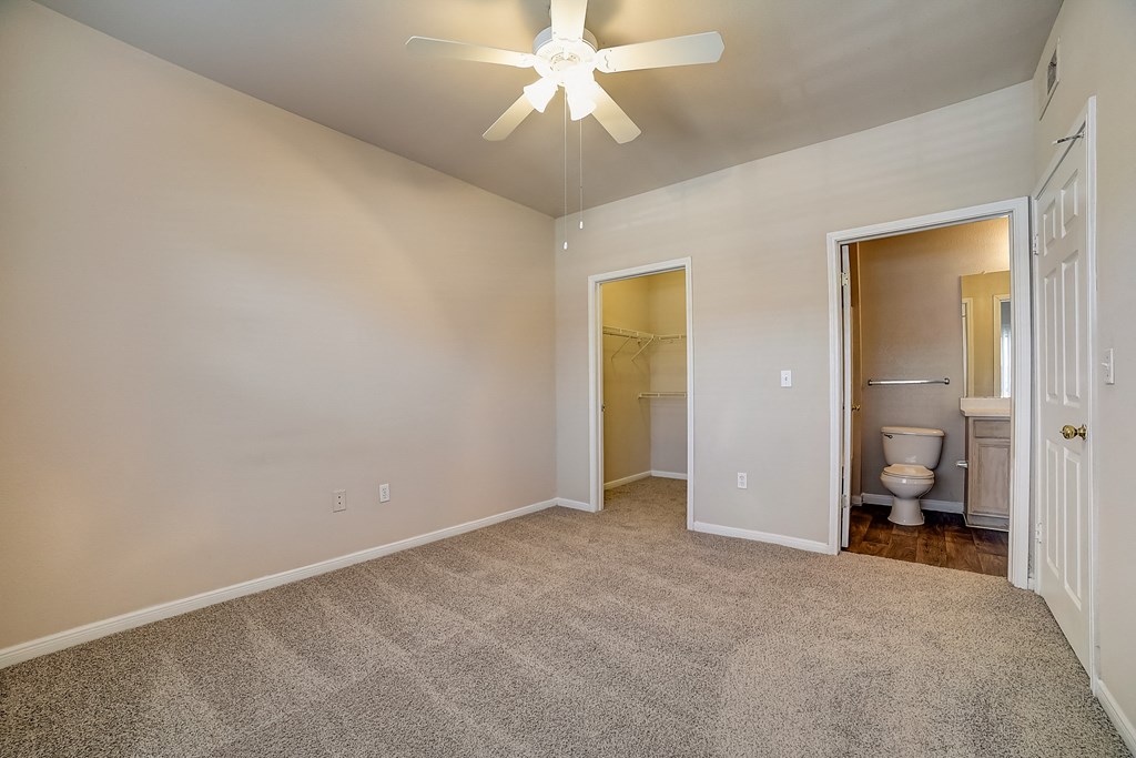 an empty living room with a ceiling fan and a bathroom