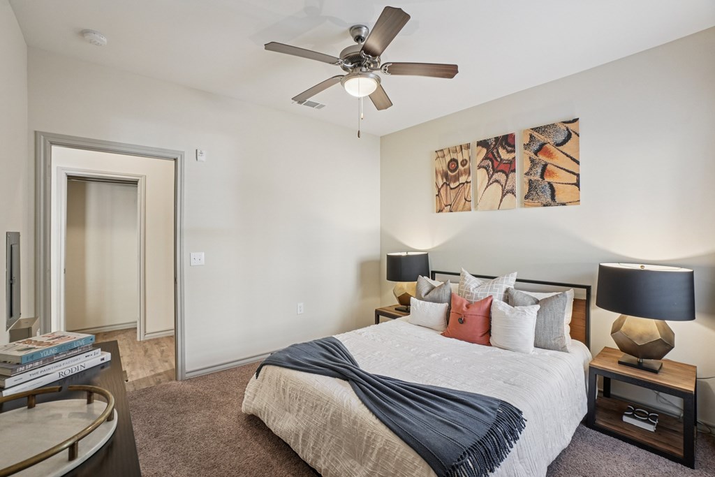 A bedroom with a bed, nightstands, and a ceiling fan.