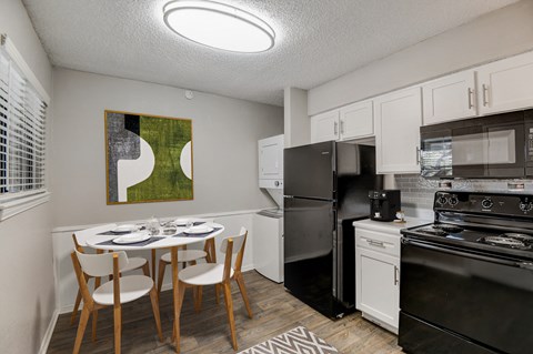 a kitchen with black appliances and a dining table and chairs