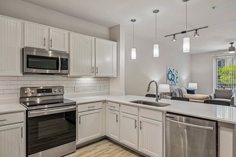A modern kitchen with white cabinets and stainless steel appliances.