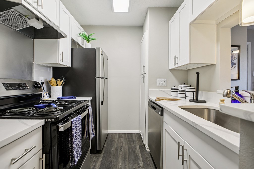 A kitchen with a black stove top oven and white cabinets.