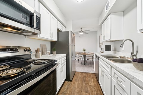 A modern kitchen with white cabinets and a black stove top.