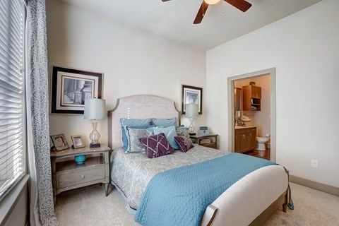 A bedroom with a bed, nightstand, and a ceiling fan.