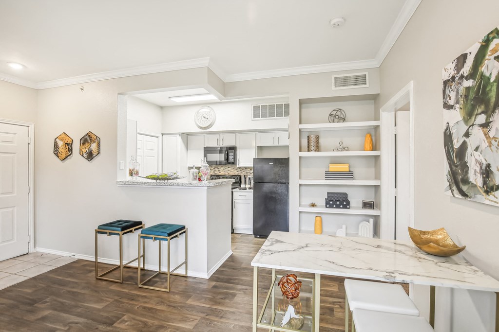 A kitchen with a white counter top and bar stools.