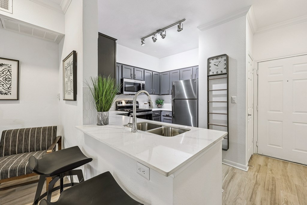 A kitchen with a white countertop and a black stool.