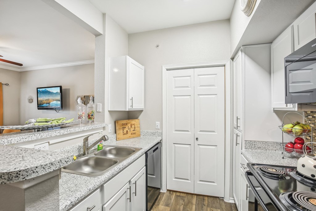 A kitchen with a sink, stove, and cabinets.