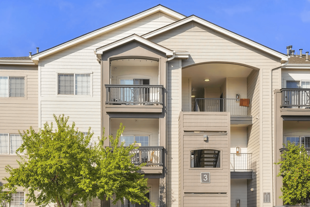 an apartment building with two balconies and a tree