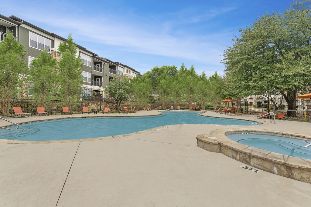 a swimming pool with two hot tubs and a building with trees