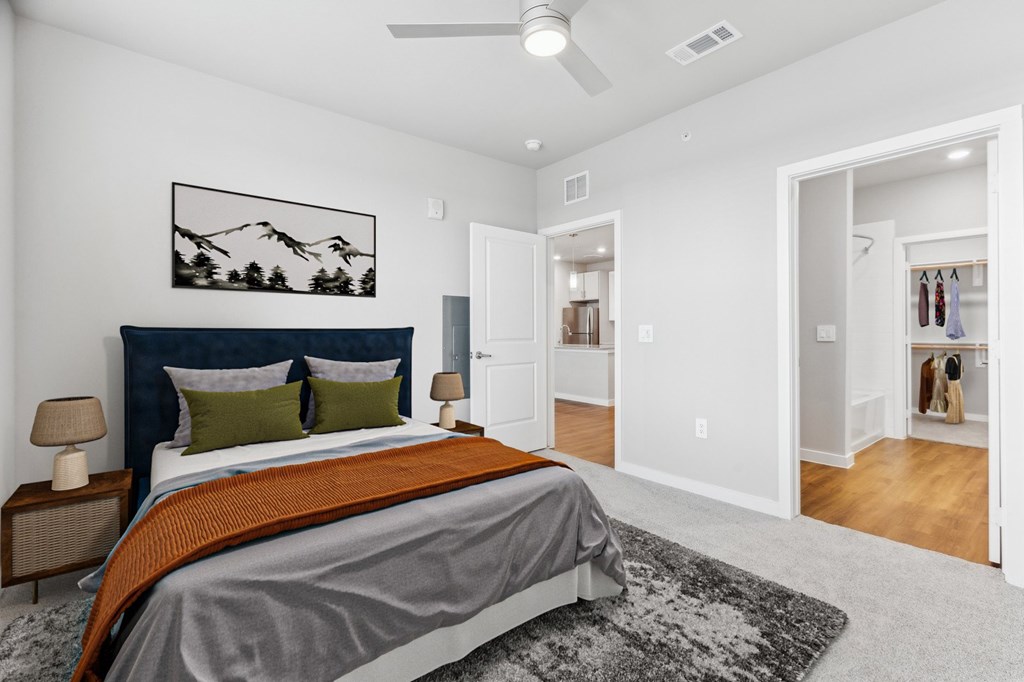 A bedroom with a bed, a rug, and a painting on the wall.