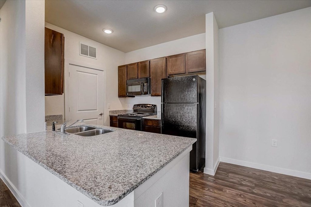 a kitchen with a granite counter top and a black refrigerator