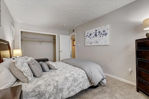 A bedroom with a large bed and a painting on the wall.