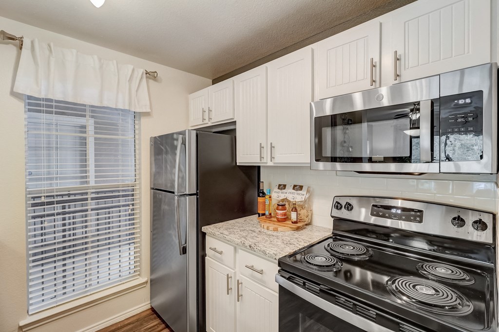 an updated kitchen with stainless steel appliances and white cabinets