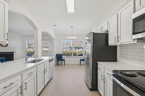 A kitchen with white cabinets and a black refrigerator.