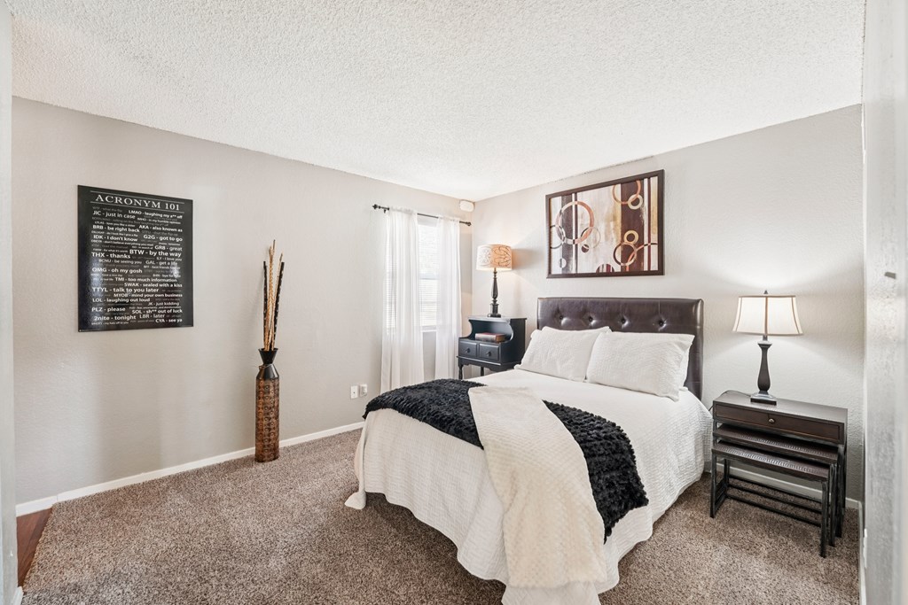 A bedroom with a bed, nightstand, and lamp.