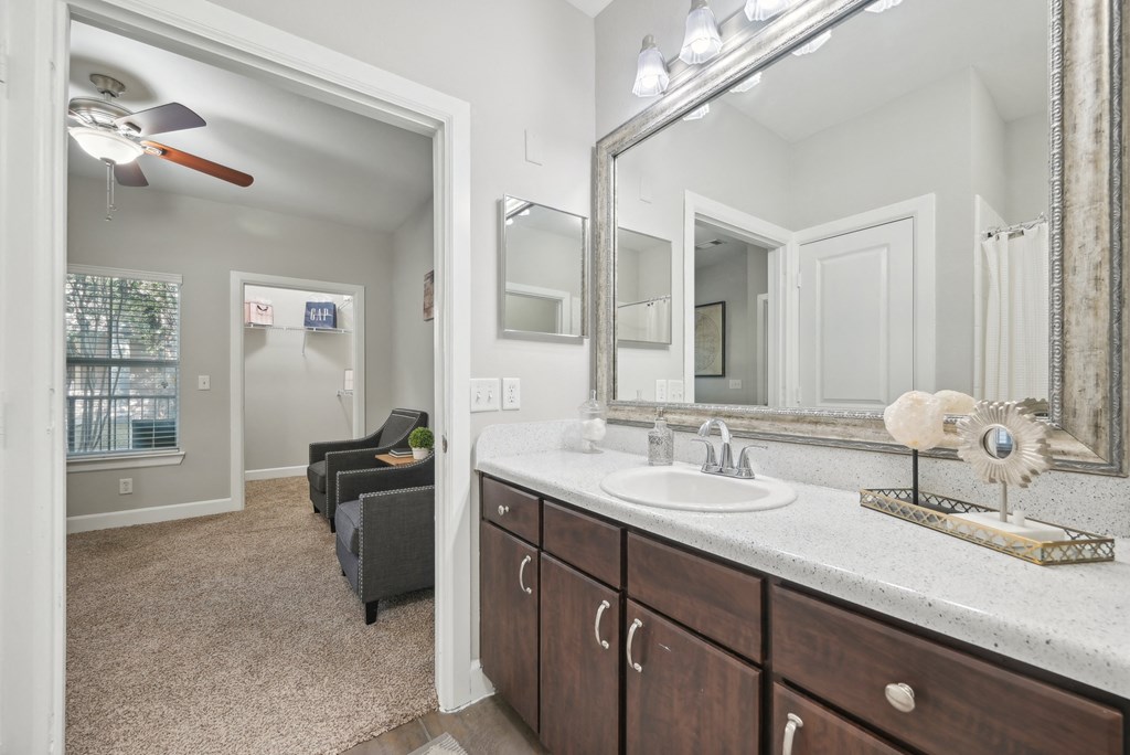 A bathroom with a vanity, a chair, and a mirror.