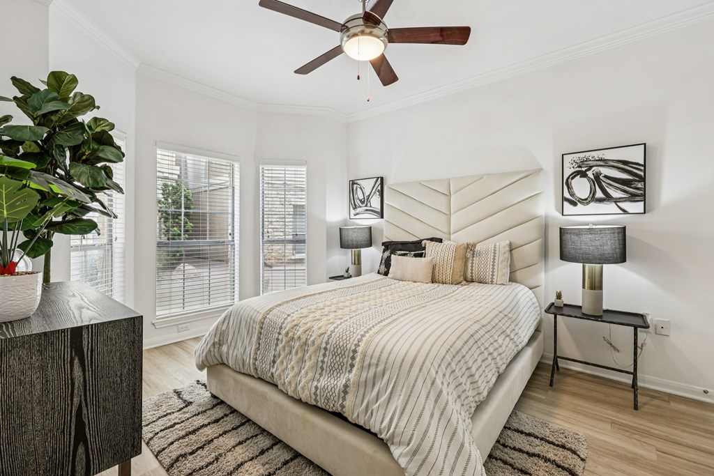 A bedroom with a bed, a side table with a lamp, and a ceiling fan.