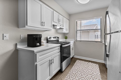 an open kitchen with white cabinets and a window and a refrigerator