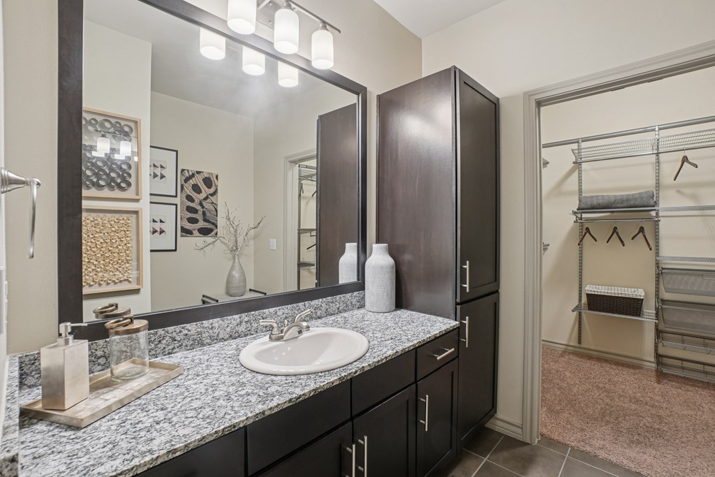 A bathroom with a sink, mirror, and cabinets.