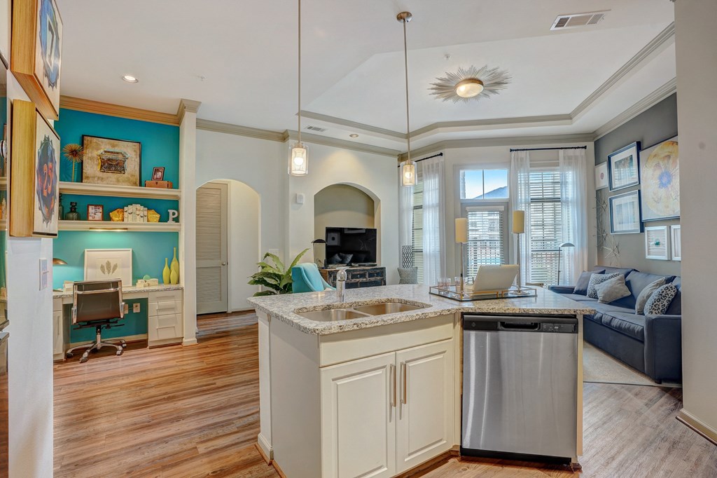 a kitchen with an island and a living room with a couch and a laptop