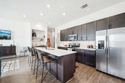 A modern kitchen with dark wood cabinets and stainless steel appliances.
