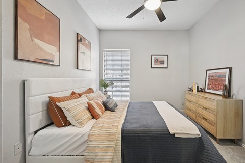 A bedroom with a bed, dresser, and artwork on the walls.