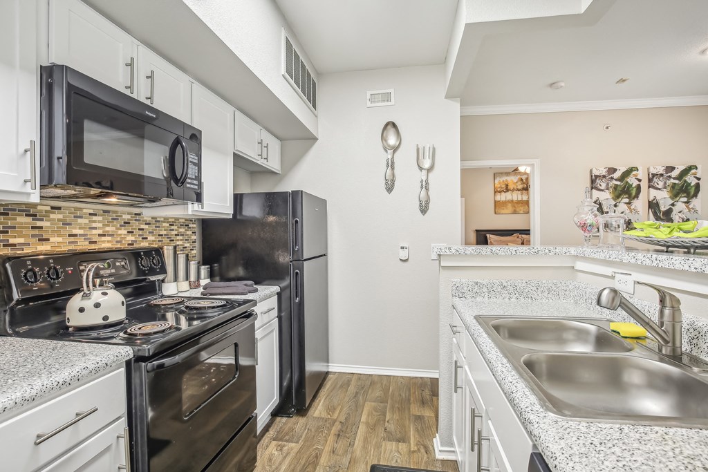 A kitchen with black appliances and white cabinets.
