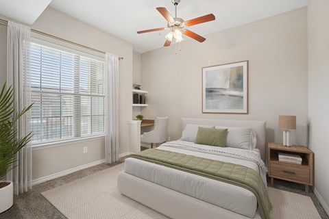 A bedroom with a large bed and a ceiling fan.