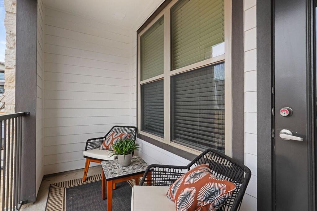 A balcony with a chair, table, and potted plant.