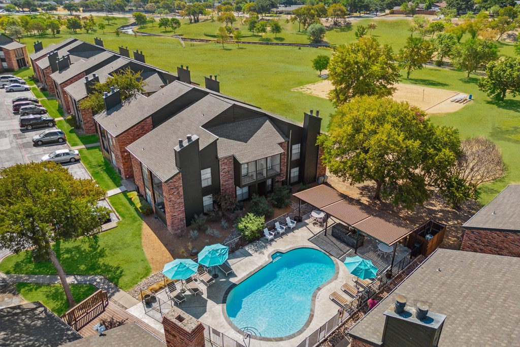 an aerial view of a house with a swimming pool and patio umbrellas