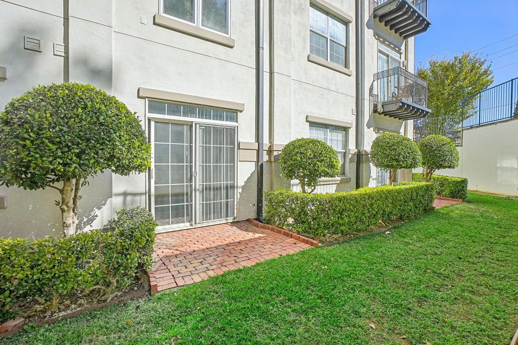 A white building with a grey door and a small tree in front of it.