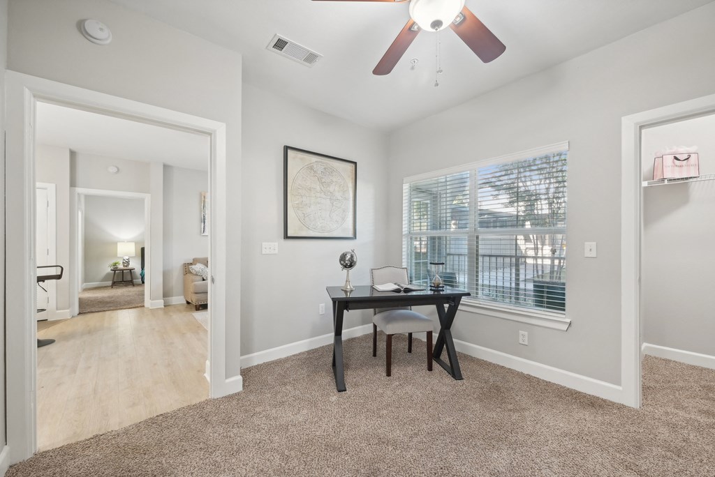 A room with a table and chairs and a ceiling fan.