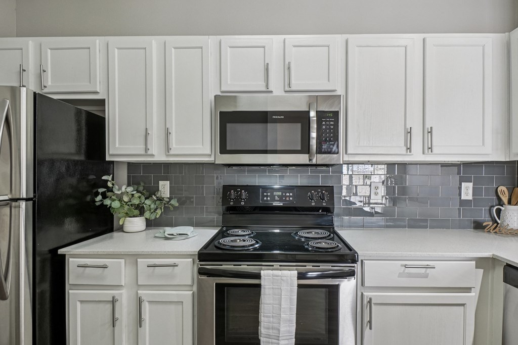 A kitchen with white cabinets and a black stove top.