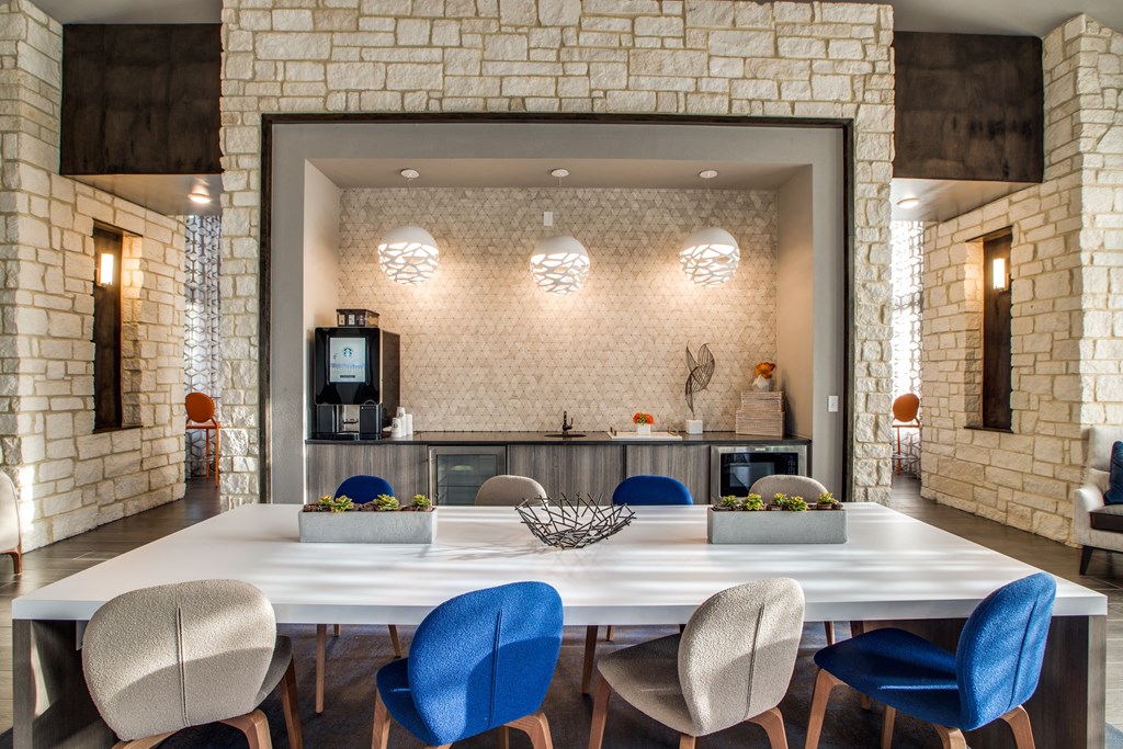 a large table with blue chairs and a kitchen in the background