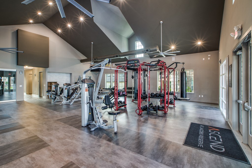 a spacious fitness center with exercise equipment and a large screen on the wall