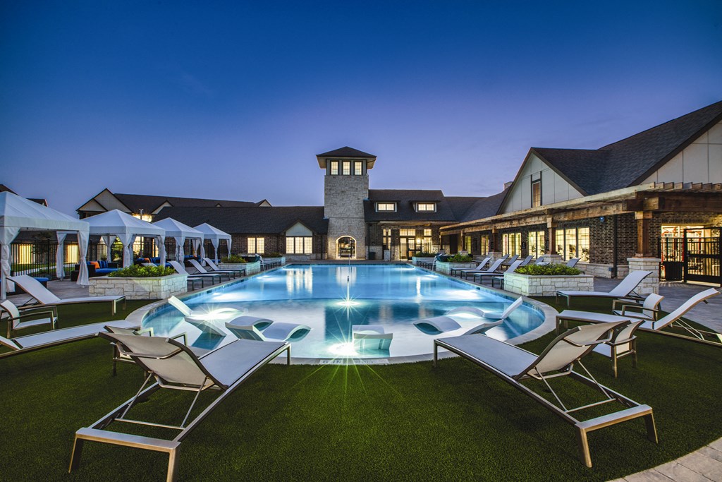a large swimming pool with lounge chairs and umbrellas
