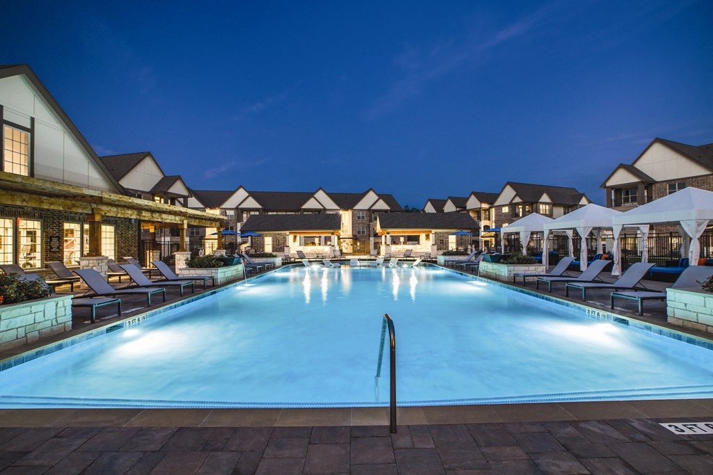 a resort style swimming pool with lounge chairs and umbrellas
