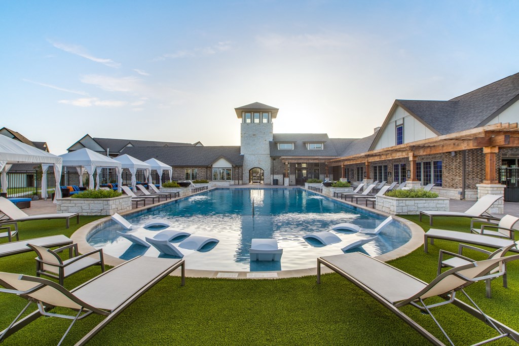 a large swimming pool with lounge chairs and umbrellas