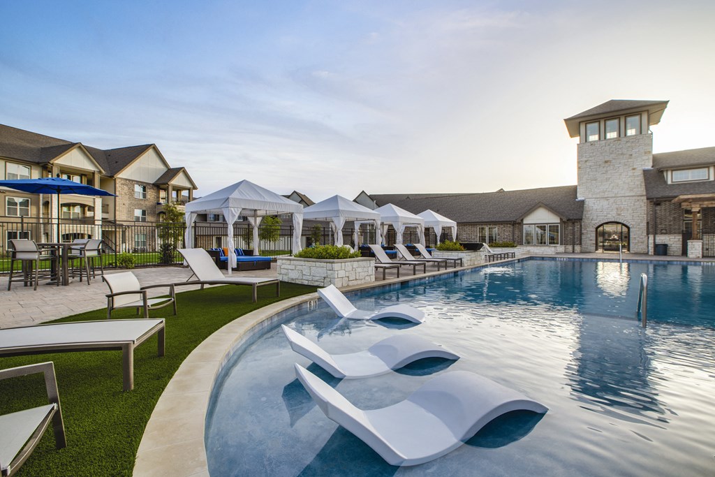 a resort style pool with lounge chairs and umbrellas
