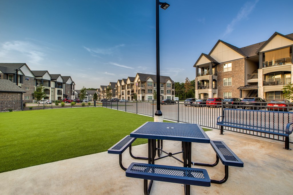 a picnic table with a view of a grassy area and apartment buildings in the background