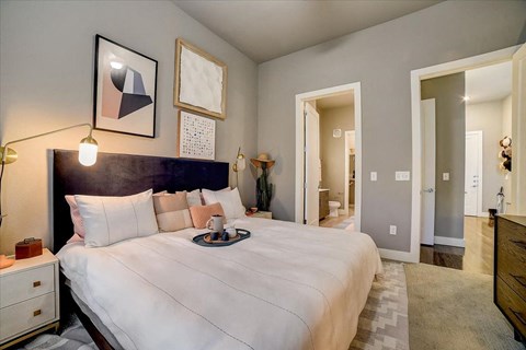 A bedroom with a large bed and a nightstand with a lamp.