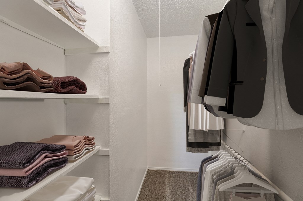a walk in closet with white walls and shelves