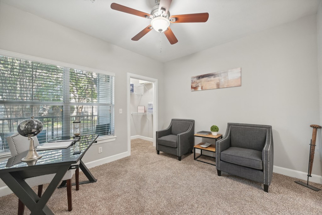 A room with a ceiling fan and three chairs.
