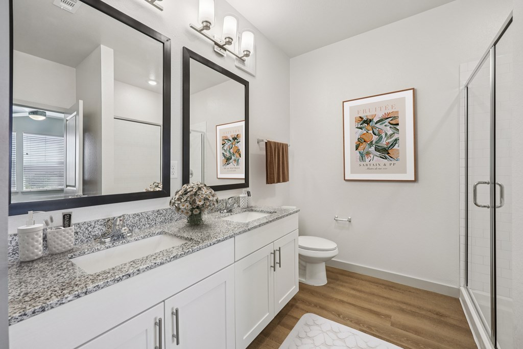 A bathroom with a toilet, sink, and a framed picture on the wall.