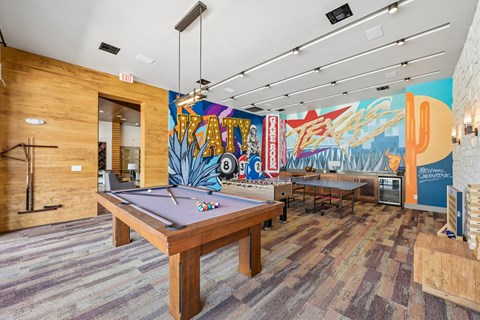 A pool table in a room with a colorful mural on the wall.