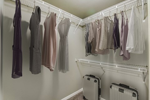 a closet with clothes hanging on a rack and luggage on the floor
