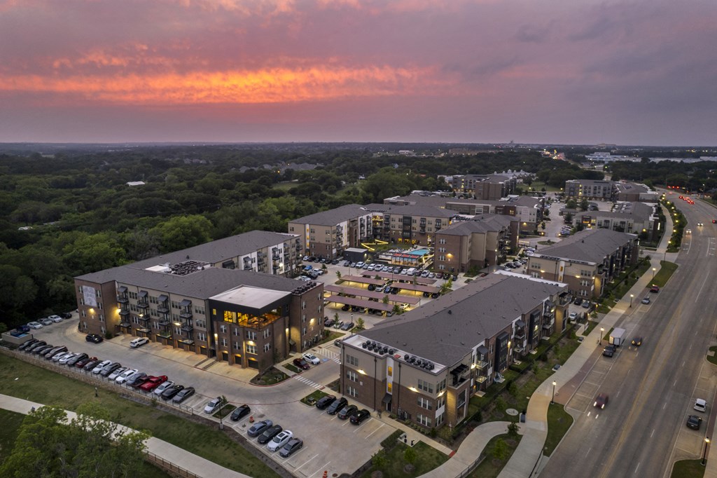 an aerial view of apartment buildings on a city street at sunset