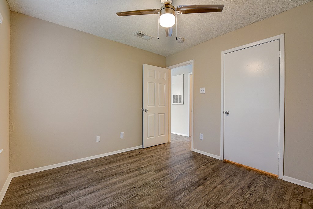an empty living room with wood flooring and a ceiling fan