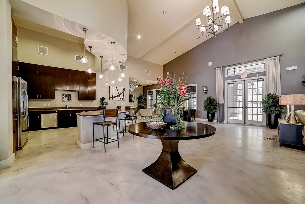 a large living room with a large chandelier and a round table with a vase