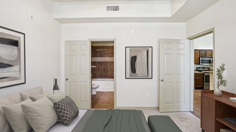 A living room with a couch, a painting, and a door leading to a bathroom.